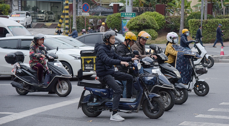 经过民警的现场纠查、宣传，市民骑车上路自觉戴头盔。（林志杰摄影） (4 - 5).jpg