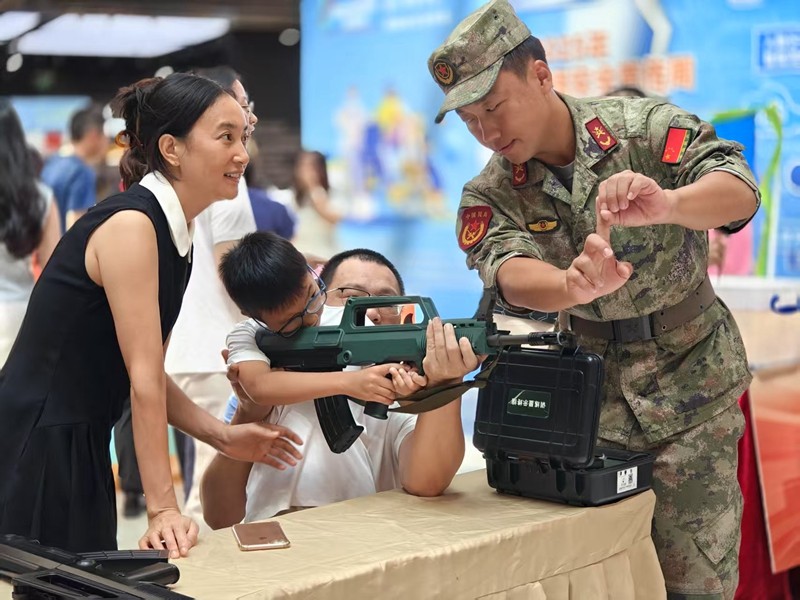 孩子在士兵的指导下体验模拟射击，感受家国情怀-许晓霞摄.jpg
