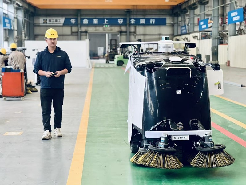 企业员工正在调试刚下线的无人驾驶清扫机器人.jpg